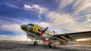 復古軍用飛機停在碎石停機坪上，天空多雲 — 美學天空 壁紙