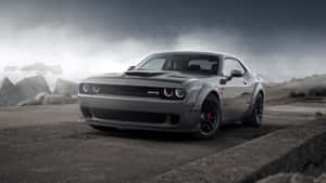 灰色 Dodge Challenger SRT Hellcat 在混凝土邊緣上，背景有暴風雨天空和岩石。 — 道奇挑戰者 壁紙