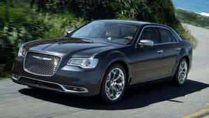 深灰色豪華轎車在日落時分沿海岸公路行駛。 — 克萊斯勒 壁紙