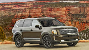深灰色Kia Telluride SUV停泊在紅色岩石峽谷景觀前。 — 起亞 壁紙