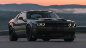 日落時分，深綠色 Dodge Challenger SRT Hellcat 在賽道上，背後有山脈和霧氣。 — 肌肉車 壁紙