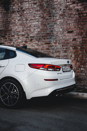 白色Kia Stinger夜間停泊在磚牆旁。 — 起亞 壁紙