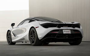 白色McLaren跑車帶黑色細節，停放在室內，背景是混凝土牆。 — 麥拉倫 壁紙