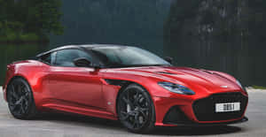 紅色Aston Martin DBS1停泊在湖邊，背景是森林覆蓋的山丘。 — 奧斯頓馬丁 壁紙