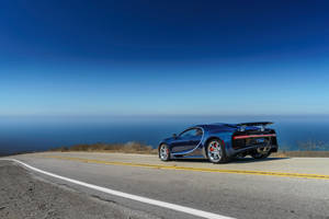 日落時分，藍色 Bugatti Chiron 在沿海公路上俯瞰海洋。 — 布加迪 GIF 壁紙