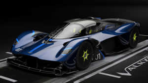 一架藍黑配色的 Aston Martin Valkyrie 超跑，在賽道上配備螢光黃色車輪。 — 奧斯頓馬丁 壁紙