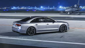 銀色 Audi 房車在夜間停在機場停機坪上，靠近私人飛機。 — 奧迪R8 壁紙