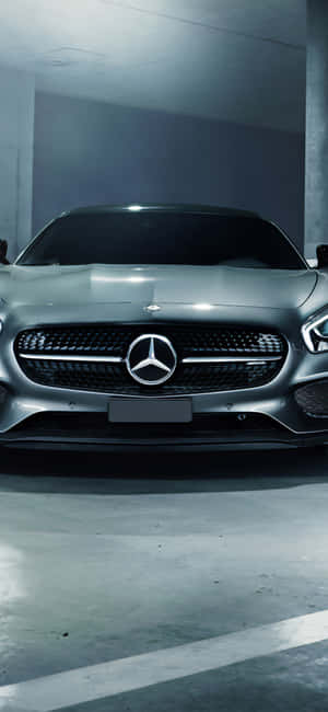 銀色 Mercedes 跑車停放在燈光昏暗的混凝土車庫中。 — iPhone 15 Plus 壁紙