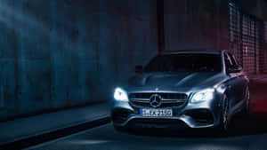 銀色 Mercedes-AMG E63 S 轎車在黑暗的城市隧道中亮著車頭燈。