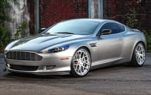 銀色Aston Martin跑車停在磚牆旁邊。 — Steam Deck OLED 壁紙