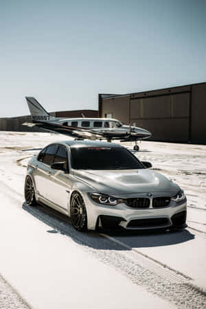 銀色BMW跑車停放在積雪的機場，旁邊是一架小型飛機。 — 小米平板 7S Pro 12.5 壁紙