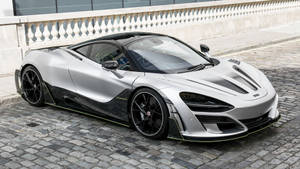 銀色McLaren Senna跑車停在鵝卵石街道上，旁邊有石欄杆。 — 白色法拉利 壁紙