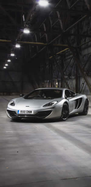 銀色McLaren跑車停放在燈光昏暗的工業倉庫中。 — 麥拉倫 720S 壁紙