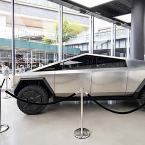 銀色Tesla Cybertruck在天鵝絨繩索和旁觀者陪同下於玻璃建築中展示。 — iPad Air 壁紙
