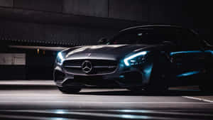 黑色 Mercedes-AMG GT 跑車停放在黑暗的地下車庫中，車頭燈發光。 — Mercedes Benz C300 壁紙