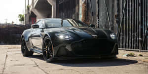 黑色Aston Martin跑車停泊在都市街道上，帶有塗鴉圍欄。 — 奧斯頓馬丁 壁紙