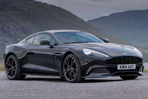 黑色Aston Martin跑車停泊在碎石上，靠近山脈。 — 奧斯頓馬丁 壁紙