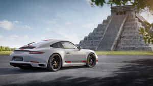 銀色保時捷911 GT3 RS在陽光下停泊在古老馬雅金字塔附近。 — 藍天 壁紙