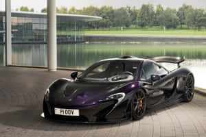 黑色McLaren P1跑車停泊在水邊和玻璃建築旁。 — 麥拉倫 壁紙