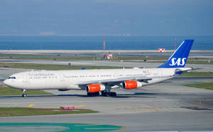 北歐航空空中巴士A330在跑道近海洋，背景有山 — 伸展台 壁紙