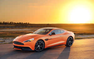 橙色Aston Martin跑車在日落時分停泊在賽道上。 — 阿斯頓維拉 壁紙