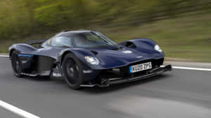 深藍色Aston Martin Valkyrie在道路上疾馳，帶有動態模糊效果。 — 奧斯頓馬丁 壁紙