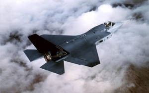 灰色X-35C戰鬥機在雲層上方飛行，飛行員可見。 — 軍事動圖 壁紙