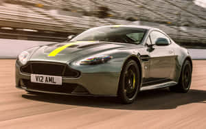 銀色 Aston Martin V12 AMR 在賽道上競速，帶有黃色點綴。 — MacBook Pro 13 壁紙