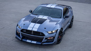 銀色Shelby GT500跑車帶有白色賽車條紋，停在混凝土上。 — 野馬GIF 壁紙