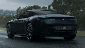 黑色Aston Martin DB11跑車在潮濕的道路上，紅色尾燈在陰天發光。 — 奧斯頓馬丁 壁紙