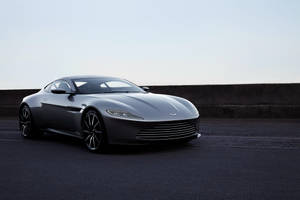 銀色Aston Martin跑車停泊在瀝青路上，靠近混凝土護欄。 — 銀色 壁紙