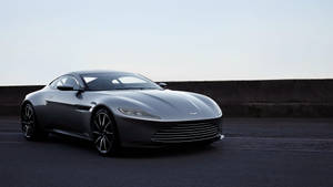 銀色Aston Martin跑車停泊在道路旁混凝土護欄邊。 — 阿斯頓維拉 壁紙