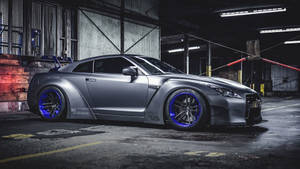 訂製消光灰色日產GT-R，藍色輪圈，置於粗獷車庫中。 — 弗萊克斯·惠勒 壁紙