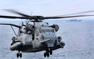 軍用直升機在海洋上空飛行，背景有軍艦。 — 軍事動圖 壁紙