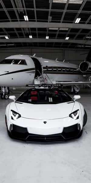 白色藍寶堅尼 Aventador 停放在機庫內的私人飛機旁邊。 — 18:9 壁紙