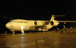 美國空軍貨機夜間停在潮濕的停機坪上，燈光亮起。 — 空軍 壁紙