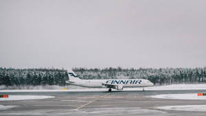 芬蘭航空飛機在雪地跑道上，背後有雪林 — 伸展台 壁紙