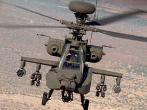 軍用阿帕契直升機飛越沙漠地形，機上裝有武器。 — 直升機 壁紙