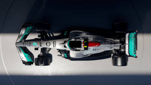 從上方俯瞰一輛帶有 Petronas 贊助的 Formula 1 賽車在混凝土表面上。 — 暗黑美學電腦 壁紙
