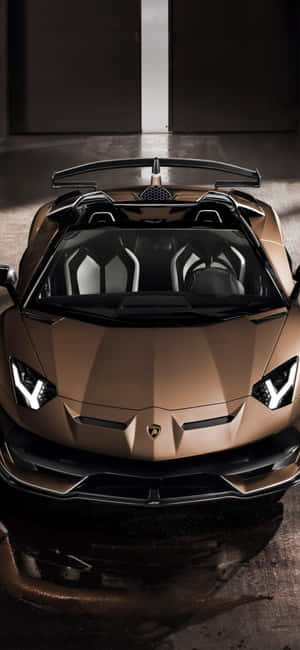 青銅色藍寶堅尼Aventador Roadster在黑暗車庫中，帶有戲劇性燈光。 — iPhone 15 Plus 壁紙