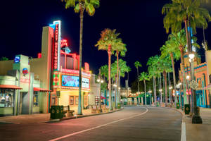 夜間街道，有棕櫚樹和 Planet Hollywood 閃爍的霓虹燈招牌。 — 好萊塢街頭 壁紙