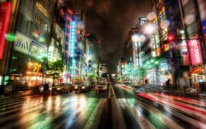 雨濕的東京街道，霓虹招牌和模糊的車燈在夜晚閃耀。 — 城市風景 壁紙