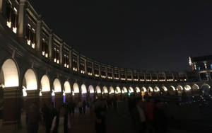 夜晚燈光下的石拱門廣場景觀，有人漫步。 — 唐人街 壁紙