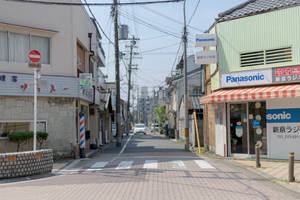 一條寧靜的日本城市街道，有商店和電線，上方是晴朗的天空。 — 東京 壁紙