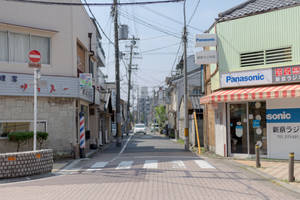 一條寧靜的日本城市街道，有商店和電線，天空晴朗。 — 街頭 壁紙