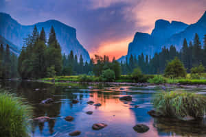 一條河流在森林覆蓋的山脈和懸崖之間反射出色彩繽紛的日落。 — 攝影 壁紙