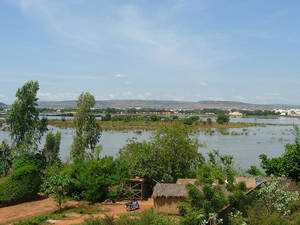 一條河流穿過綠色的景觀，有茅草屋和樹木，天空湛藍。 — 藍天 壁紙