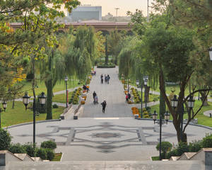 人們沿著鋪砌的公園小徑行走，在樹蔭下的長椅上放鬆。 — 烏茲別克 壁紙