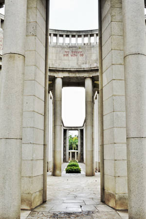 帶有柱子和刻字的石製紀念拱門，通往花園。 — 2:3 壁紙