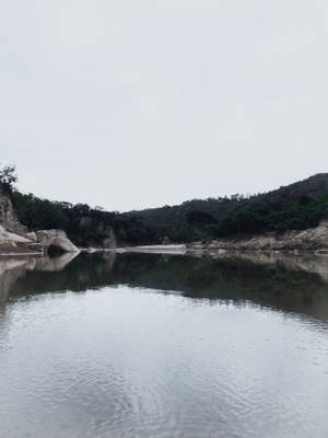 寧靜的河流映照著灰色的天空和森林覆蓋的山丘。 — 宏都拉斯 壁紙